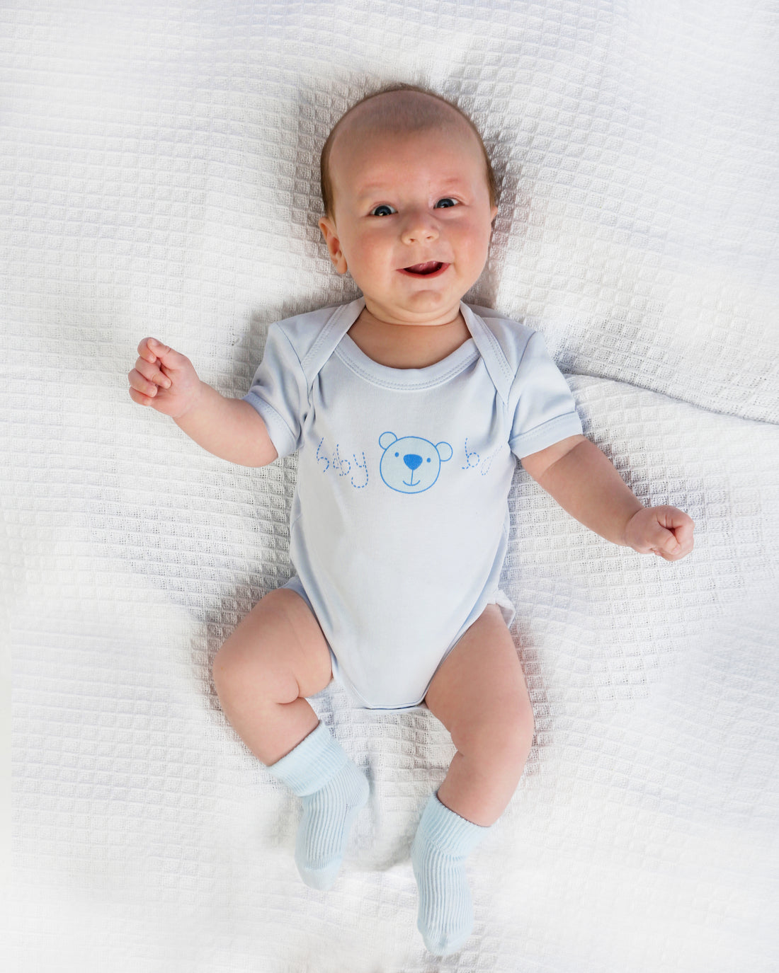 Baby boy in blue cotton vest outfit, with blue turnover socks.