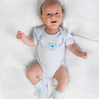 Baby boy in blue cotton vest outfit, with blue turnover socks.